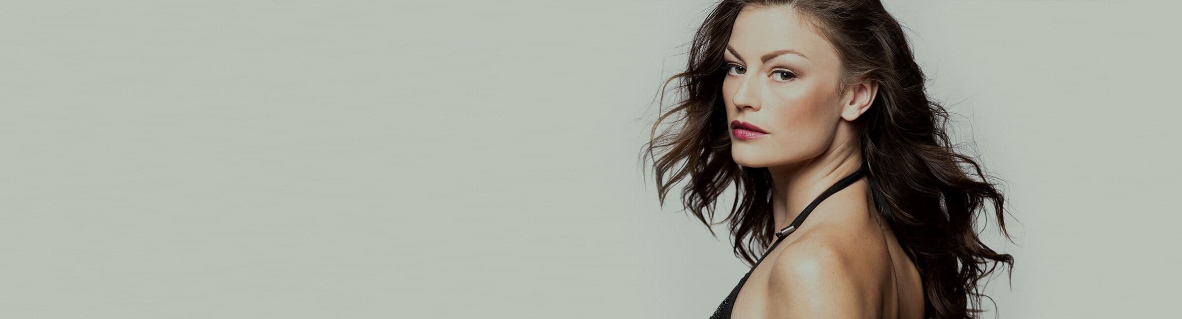 Editorial portrait of a woman with clear, even skin against a light neutral backdrop